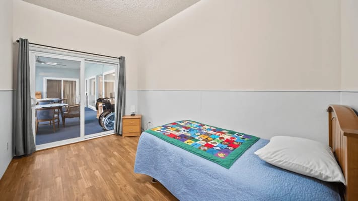 A cozy resident room with a patchwork quilt and sliding glass door