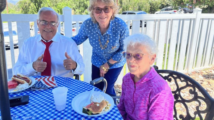 Residents enjoying a meal outdoors at a table