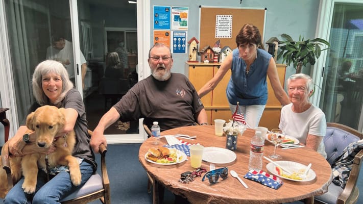 Residents enjoying a meal, socializing, and a dog