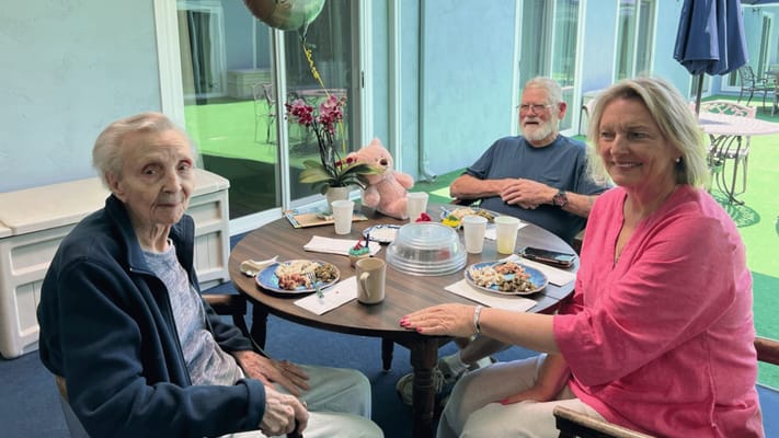 Three residents enjoying meals together outdoors