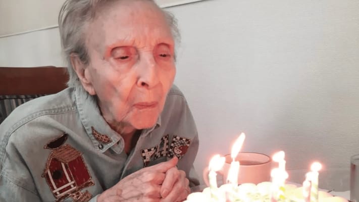 Elderly woman blowing out birthday candles on a cake
