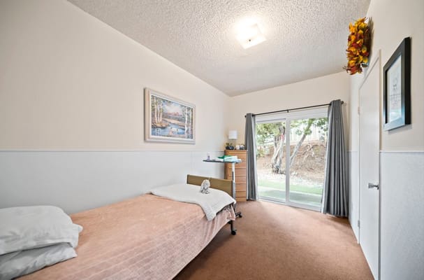 A private resident room with a bed and patio access