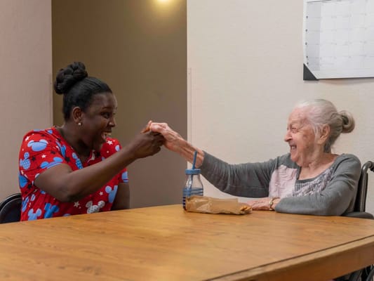 Caregiver and resident sharing a joyful moment at a table