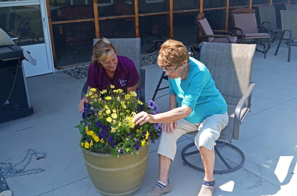 Staff member and resident tending to flowers outside
