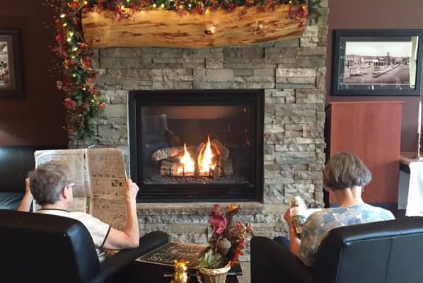 Residents relaxing by the fireplace in a cozy lounge area