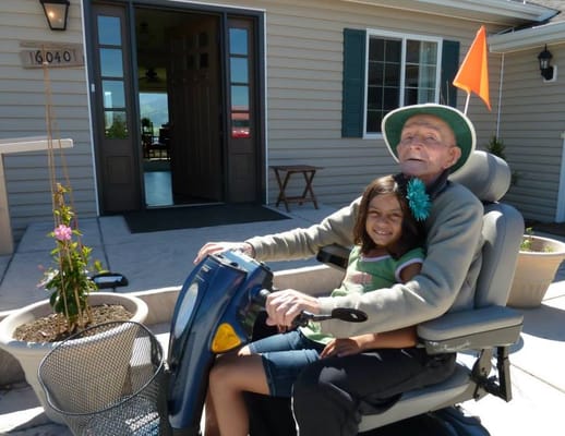 Elderly man with child on mobility scooter outside the facility