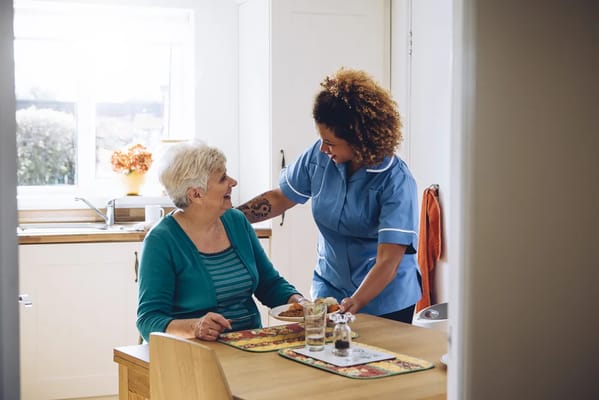 A caregiver serving food to a senior resident