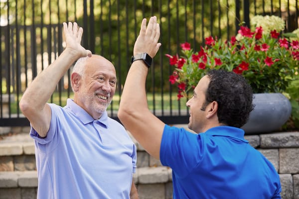 Two men giving a high-five in a garden area