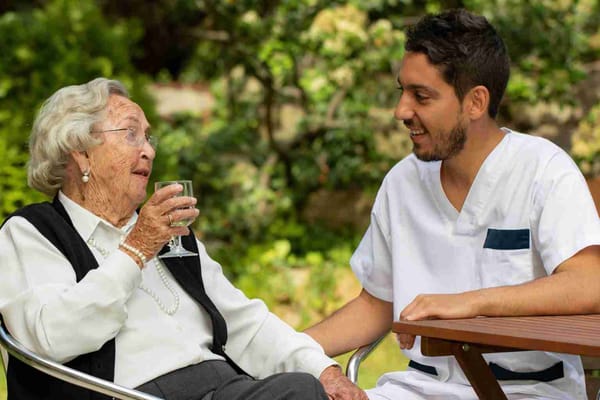 Resident enjoying a drink outdoors with staff member