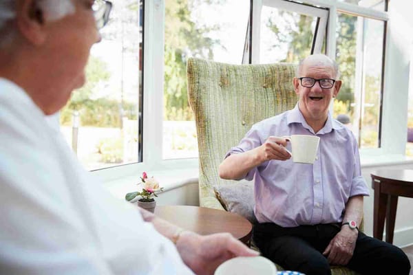 Residents smiling and enjoying tea in a common area