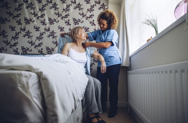 Care staff assisting a resident in a bedroom