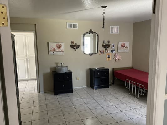A cozy bedroom featuring a bed, dresser, and decorative wall art.