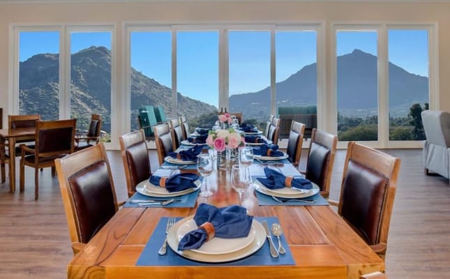 Elegant dining setup with a view of mountains through large windows.