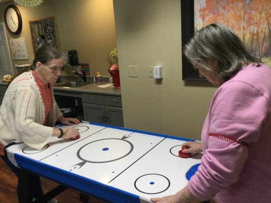 Two residents playing air hockey in an activity room