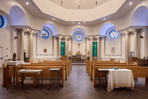 Interior view of a chapel with wooden pews and stained glass windows