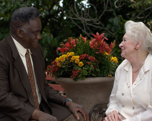 Two residents enjoying a conversation in a garden setting.