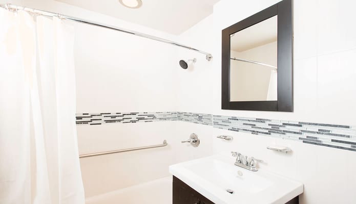 A modern bathroom with a shower, sink, and mirror.