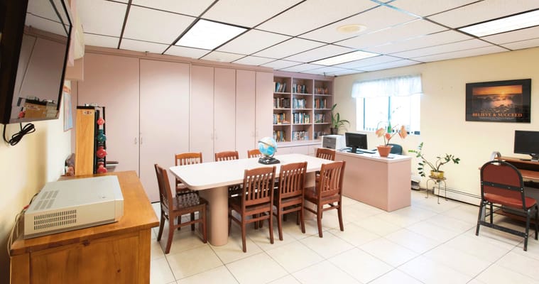 A common room featuring a long table, chairs, bookshelves, and a globe.