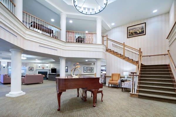 Spacious lobby featuring a grand piano and stairway