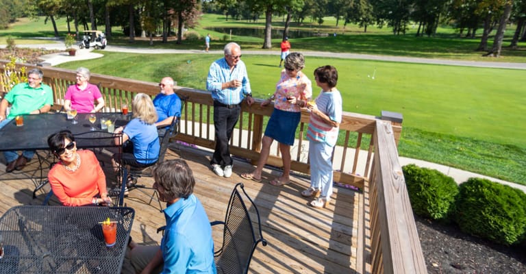 Residents socializing on a patio overlooking a golf course