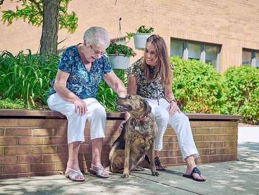 Resident and staff member enjoying time with a dog outside