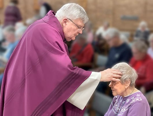 A staff member performing a blessing on a resident