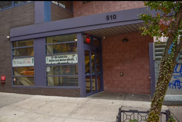 Front entrance of VillageCare at 46 & Ten with a saluting healthcare workers banner