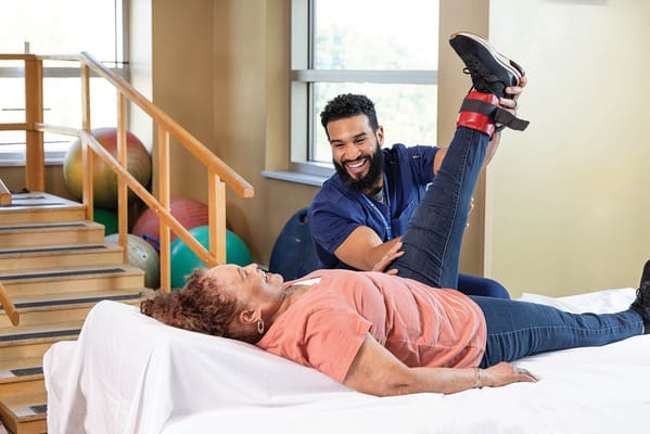 Therapist assisting resident with leg exercises