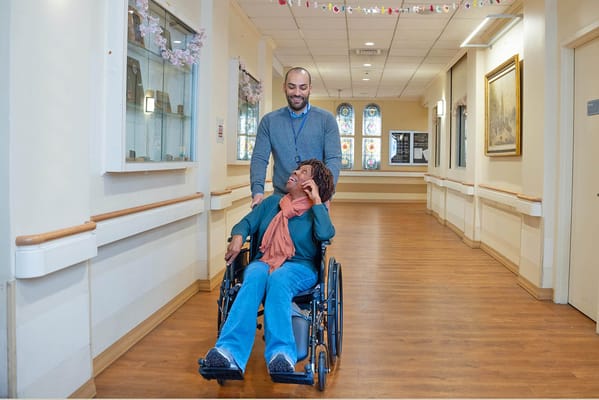 Staff assisting a resident in a hallway.
