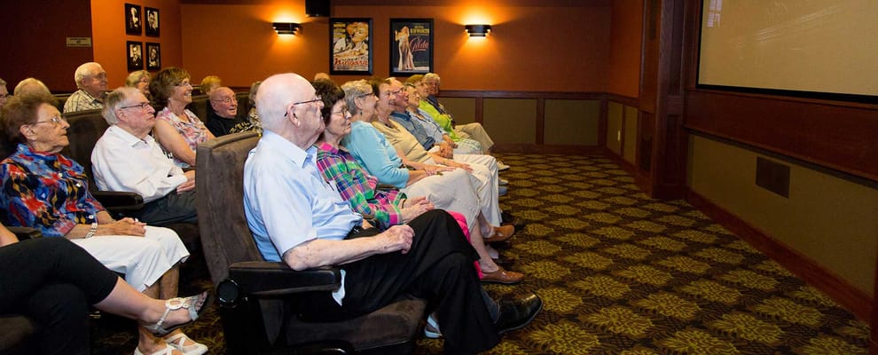 Residents enjoying a movie in a well-lit theater room