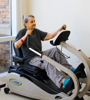 Resident using a NuStep exercise machine in the facility