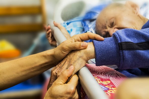 Caregiver holding the hand of an elderly resident