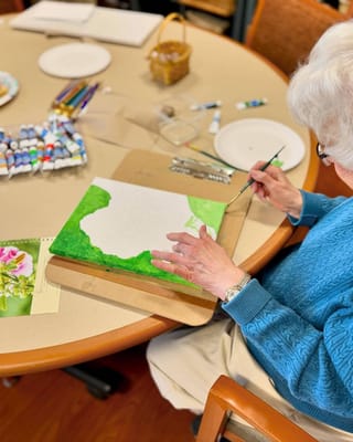 Resident painting in a bright activity room