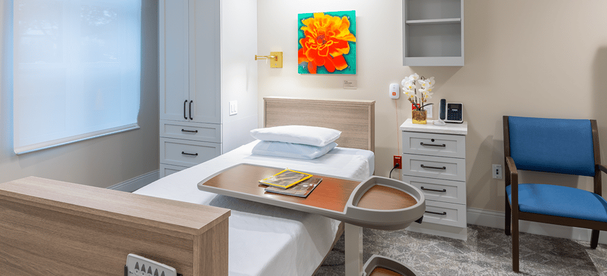 A brightly lit resident room with a bed and artwork