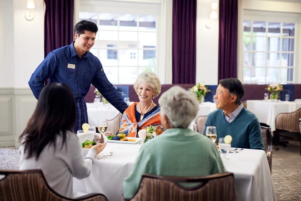 Residents enjoying a meal in a dining room with staff