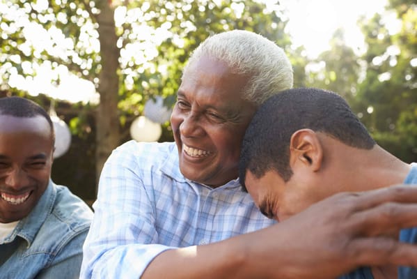 Three men laughing together outdoors in a joyful moment