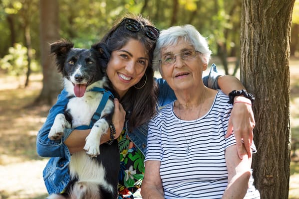 A caregiver and a resident enjoying time outdoors with a dog