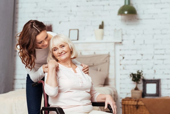 A caregiver smiling with a resident in a homey room