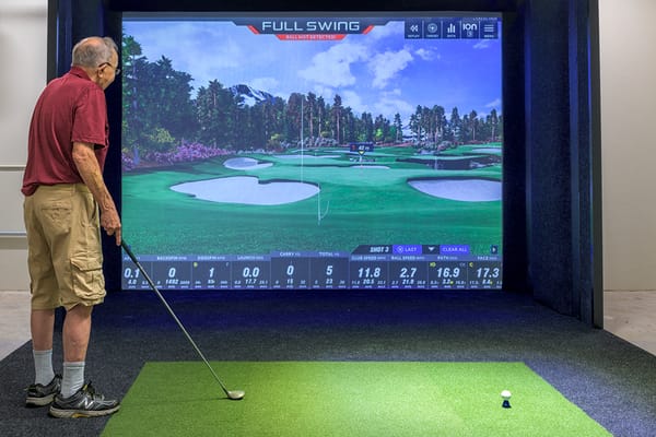 Resident using a golf simulator in an activity room
