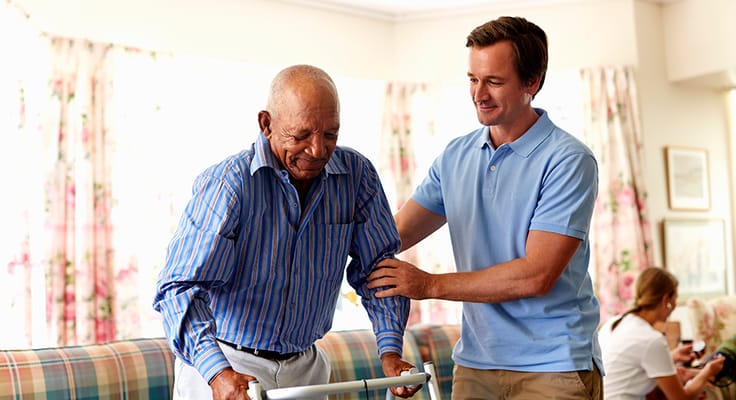 A caregiver assisting an elderly resident in a common area