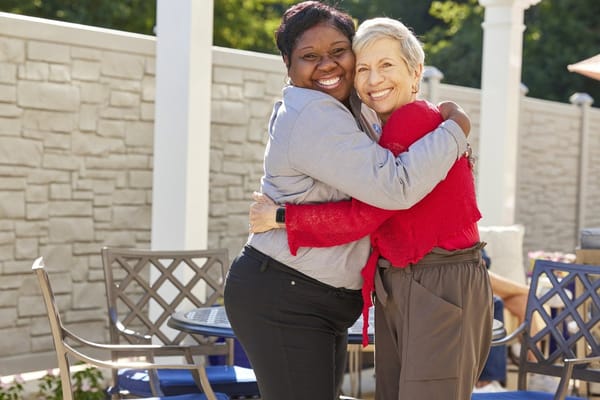Two women joyfully embracing in an outdoor setting