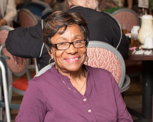 A smiling senior woman sitting in a dining area