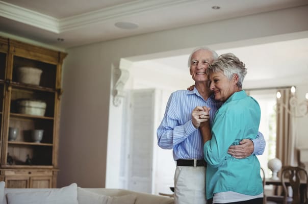 A happy elderly couple dancing in a bright room
