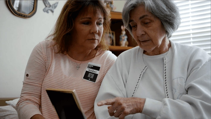 A caregiver and a resident looking at a photo together