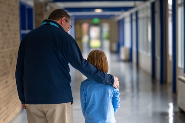 A staff member accompanying a child down a hallway