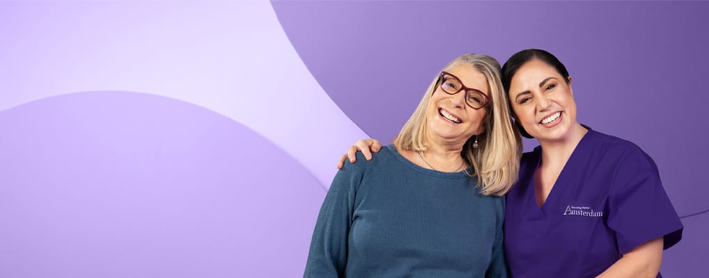 A resident and caregiver smiling together in a caring environment.