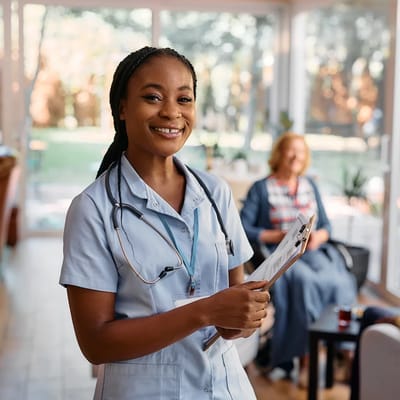 A smiling nurse holding a clipboard in a bright common area