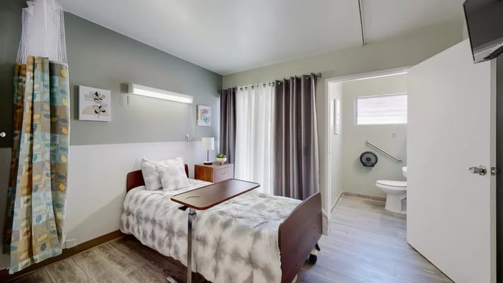 A well-lit private resident room with bed and bathroom