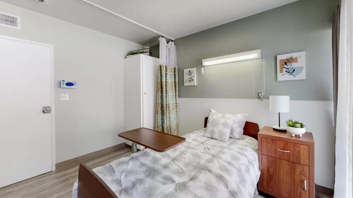 Neatly arranged private resident room with bed and furniture