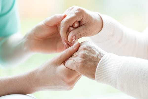 A caregiver holding a senior's hand in a caring gesture